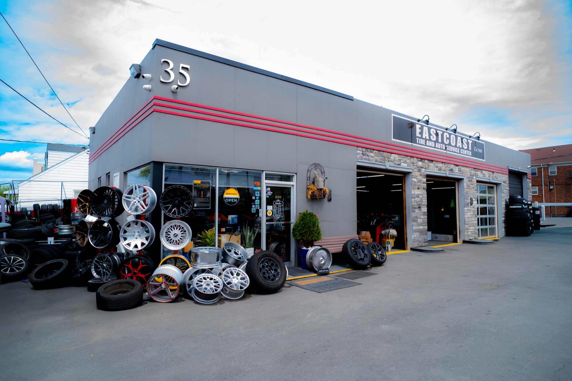 East Coast Auto Sport at 35 Schuyler Avenue: gray storefront with red trim, wheel displays and service bays
